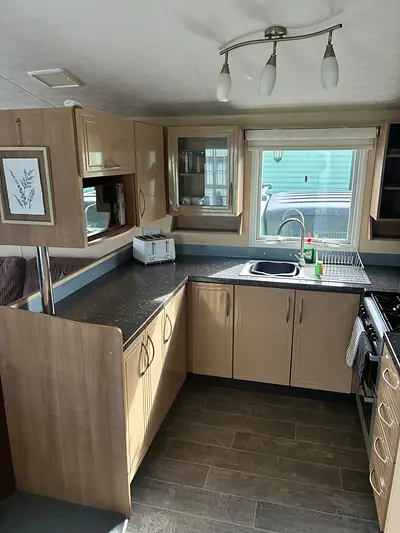 The kitchen in The Lake District Caravan with a blue splashback.