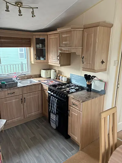 The kitchen in The West Lakes Caravan with light wood units and a gas cooker.